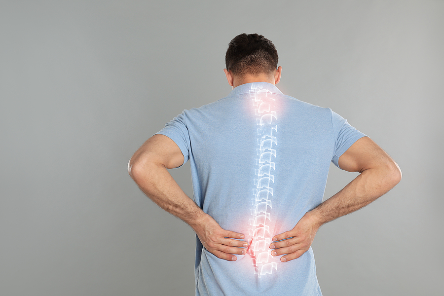 Man experiencing back pain, highlighting symptoms of Ankylosing Spondylitis affecting the spine.
